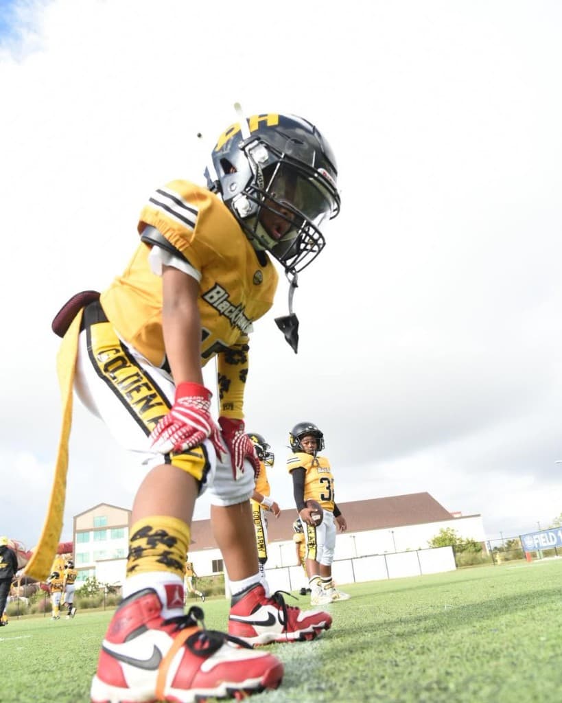 An AYF football player in a yellow jersey lined up on the field