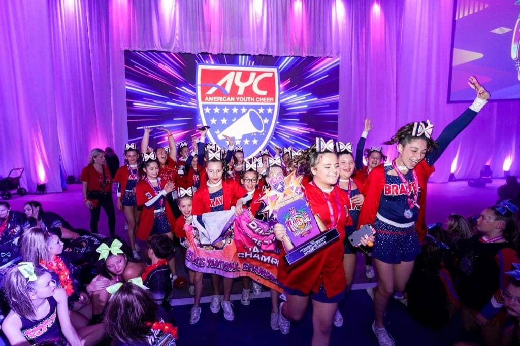 Cheerleaders celebrating with a trophy on stage