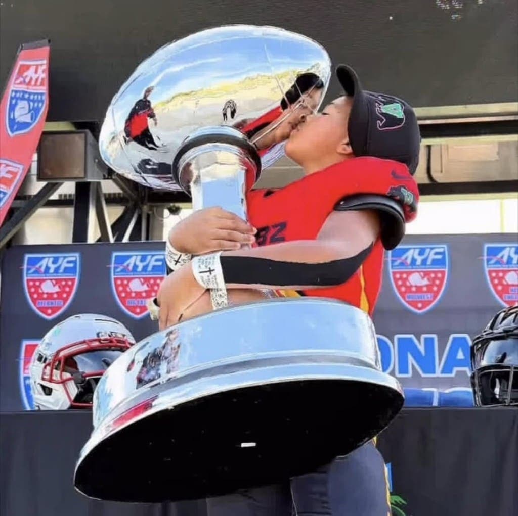 A football player kissing a championship trophy