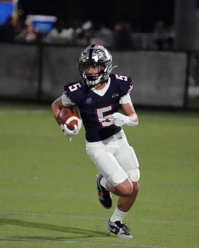 A football player carrying the ball during a night game